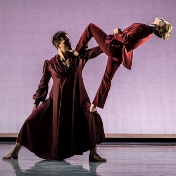 Two dancers in red outfits performing on stage.