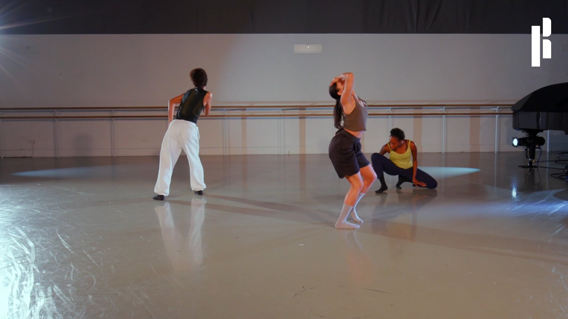 A group of dancers in a room with a piano.