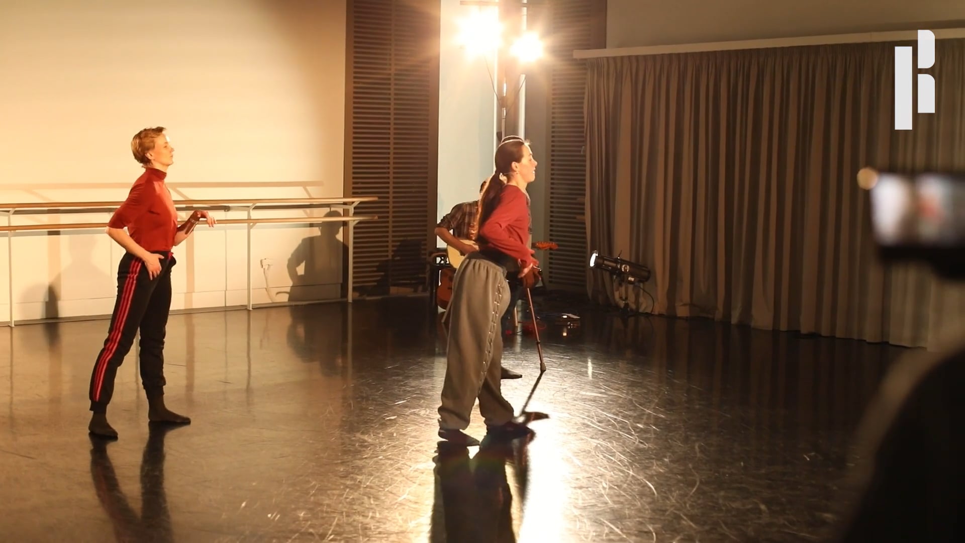 Two dancers in a dance studio with a camera.