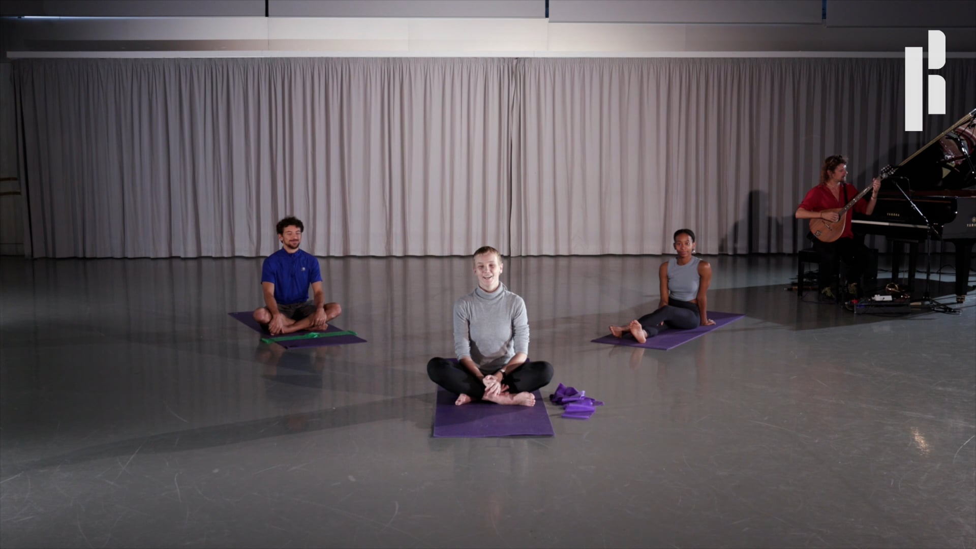 A group of people sitting on yoga mats in front of a piano.