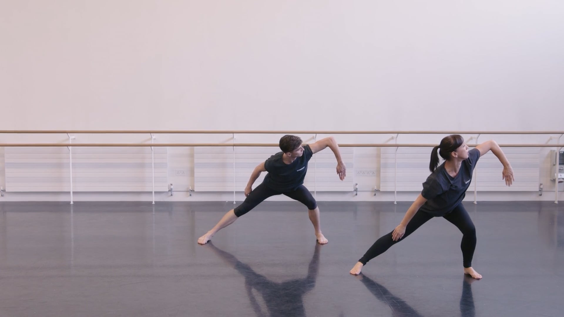 Two dancers practicing in a dance studio.