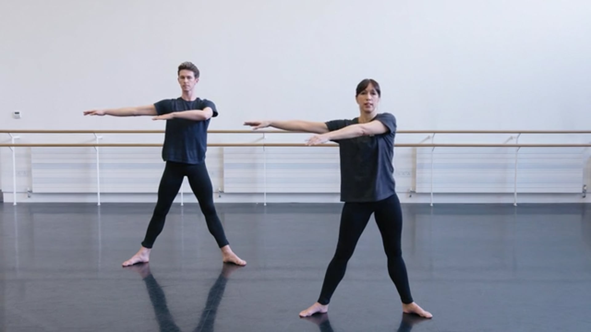 Two dancers practicing in a dance studio.