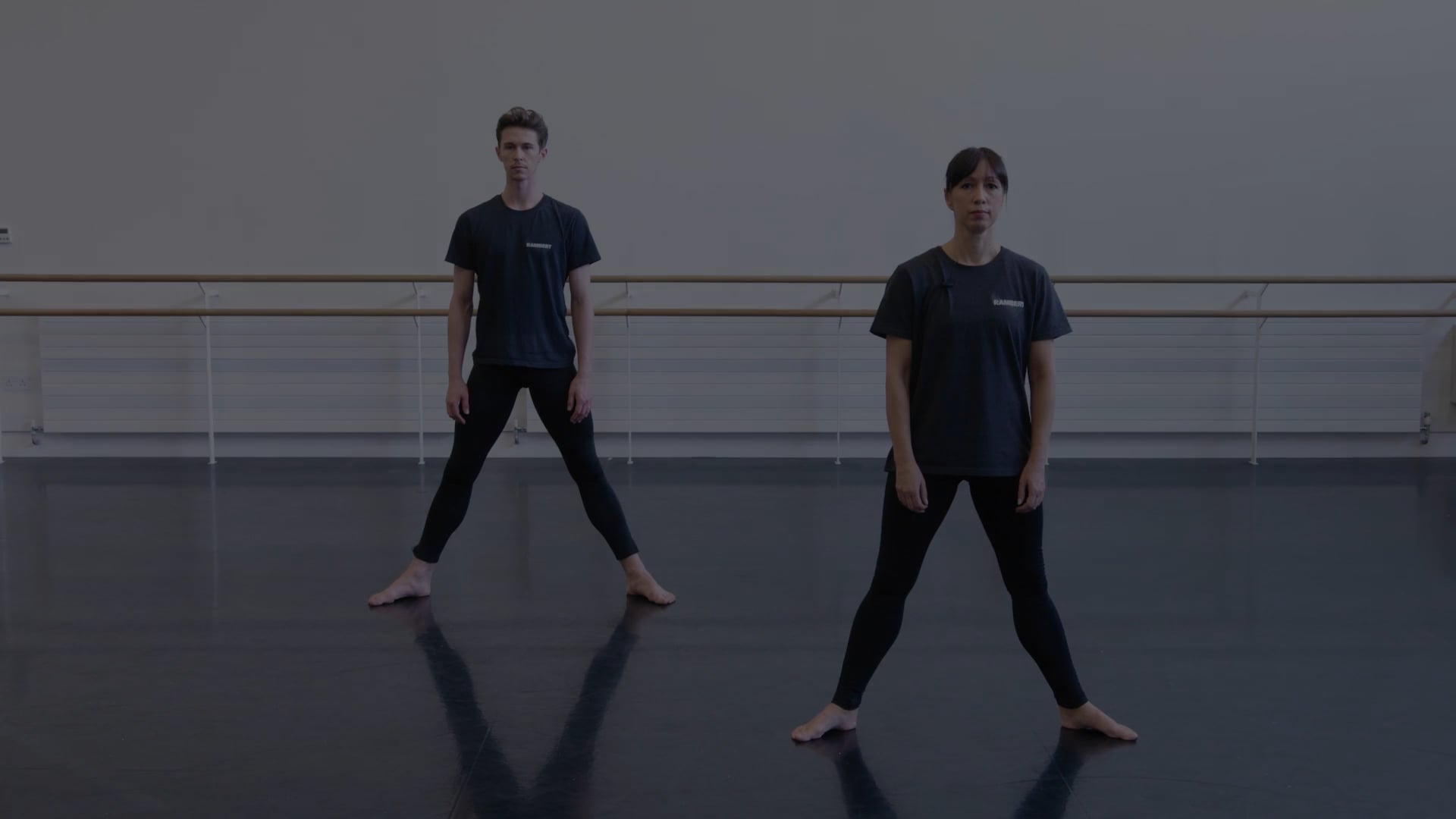 Two dancers standing in a dance studio.