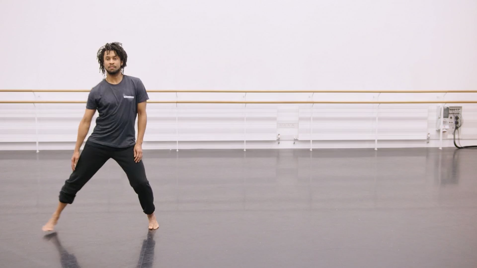 A man in a black shirt is standing in a dance studio.