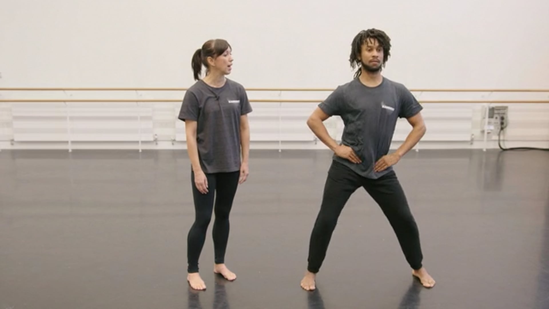 Two dancers standing in a dance studio.