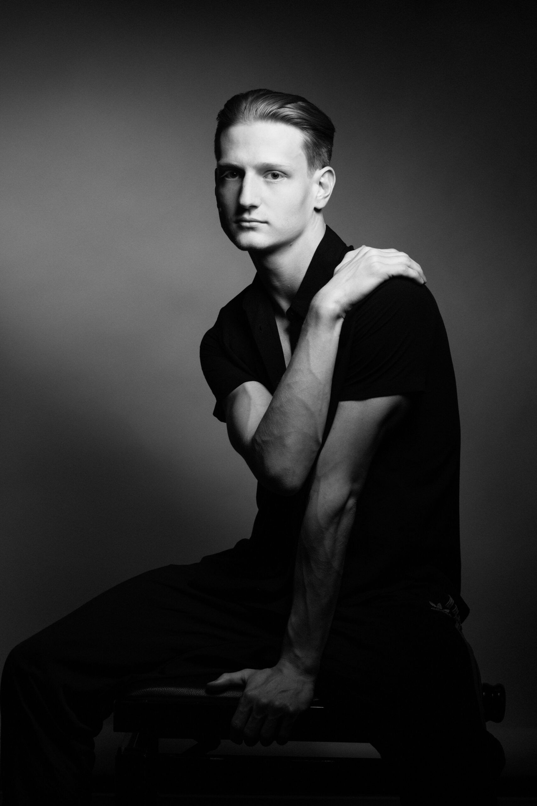 a black and white photo of a man sitting on a stool.