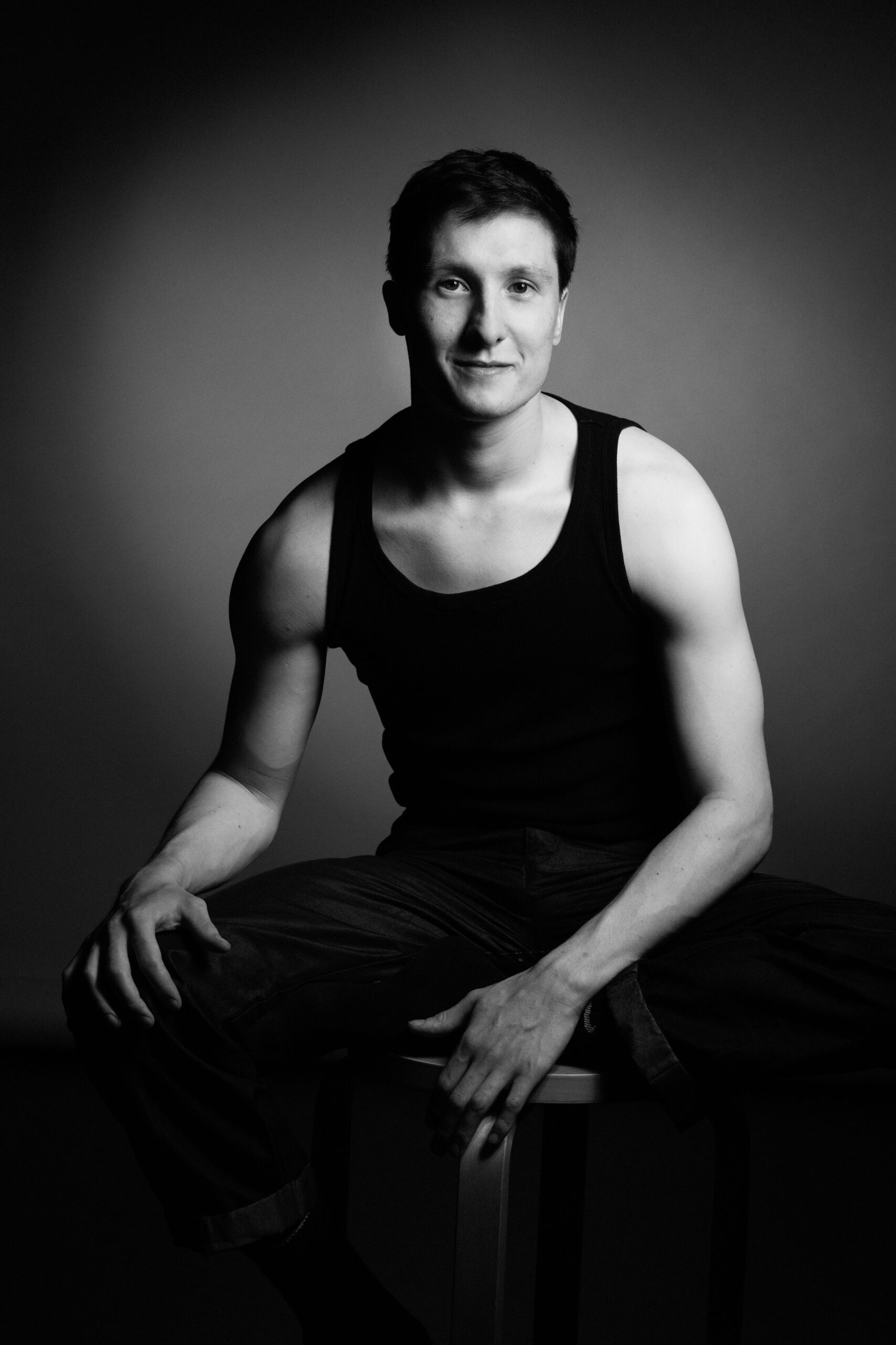 a man in a tank top sitting on a stool.