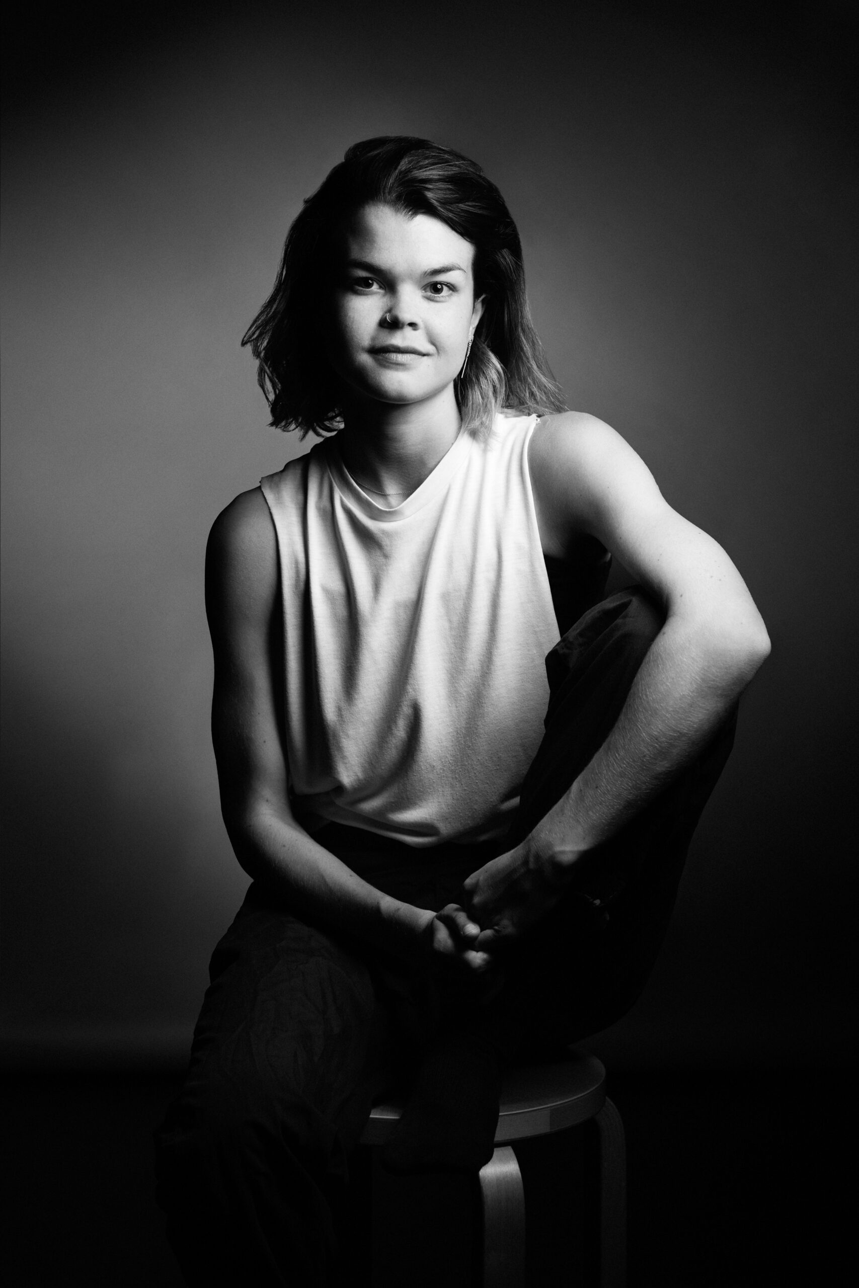 a black and white photo of a woman sitting on a stool.