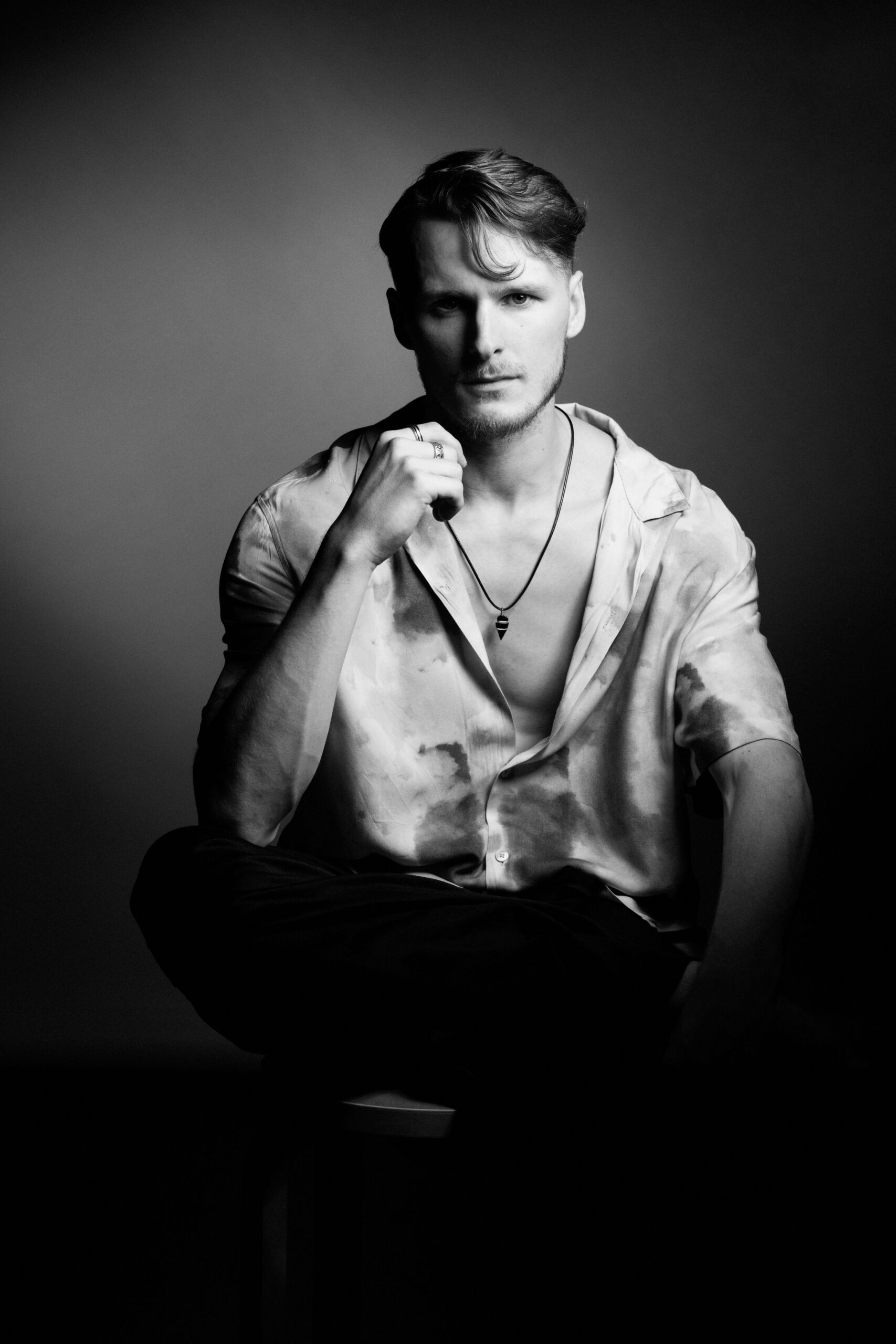a man sitting on top of a stool in a black and white photo.