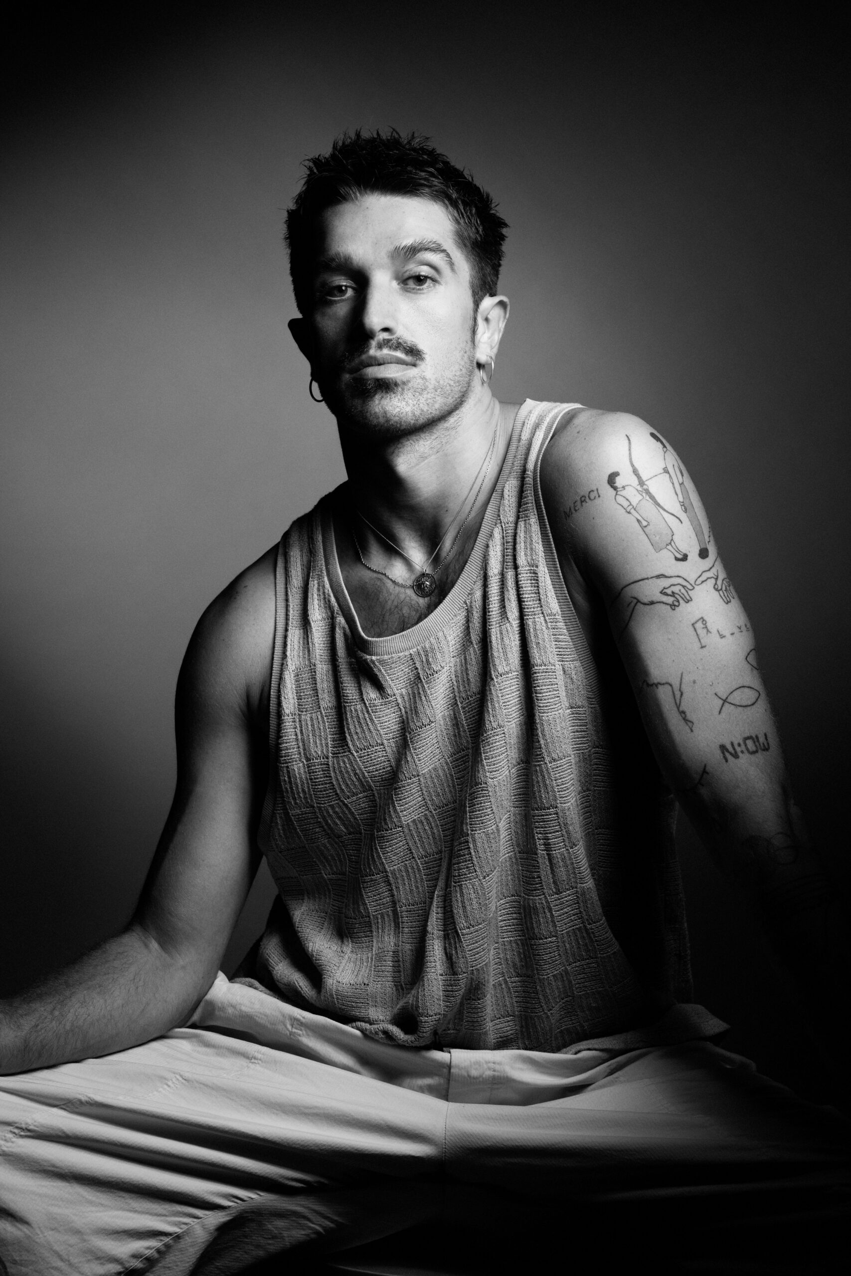 a man with tattoos sitting on a bed.