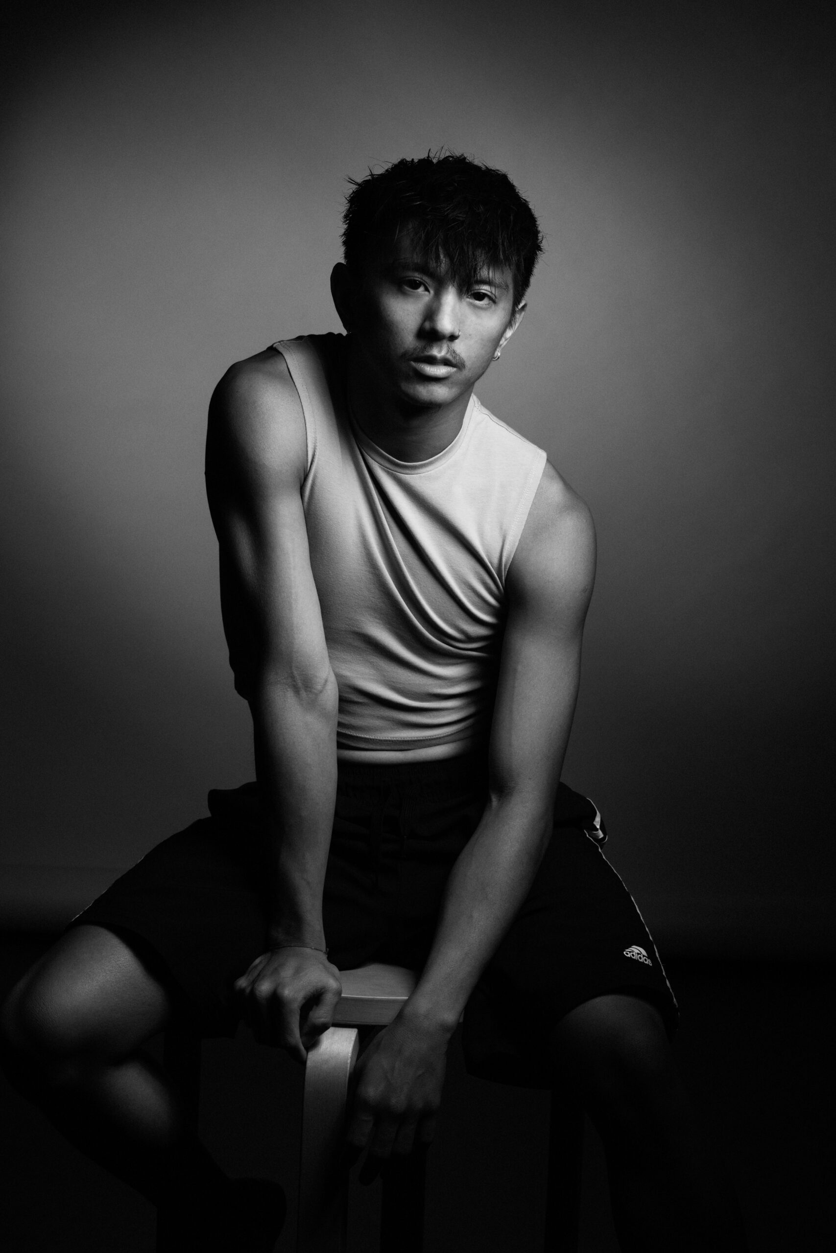 a man sitting on a stool in a black and white photo.
