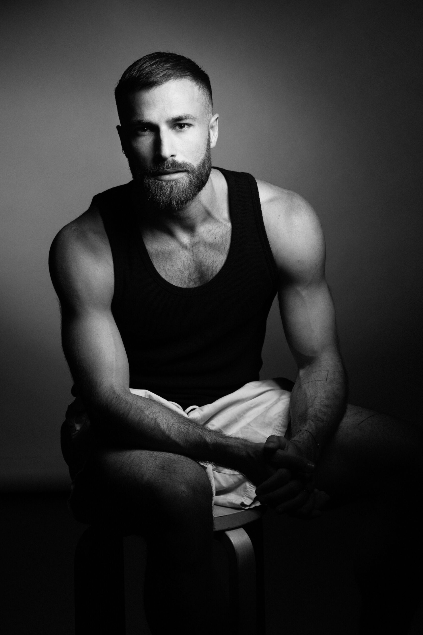 a man with a beard sitting on a stool.