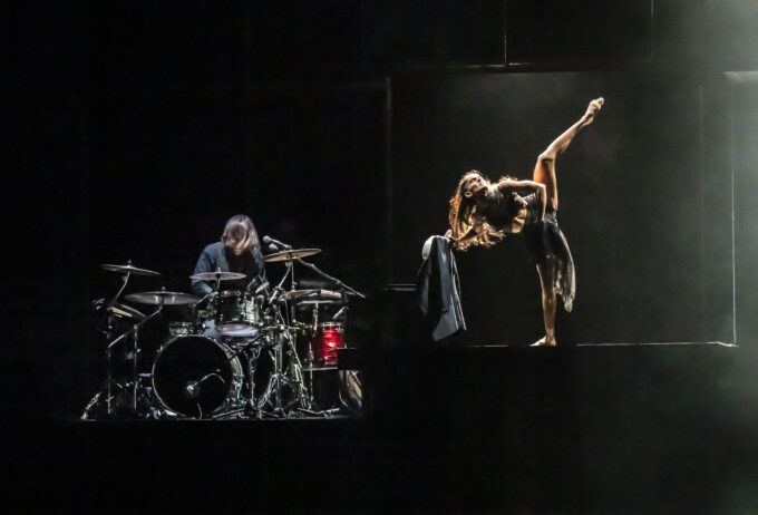 a woman standing on a stage next to a drummer.