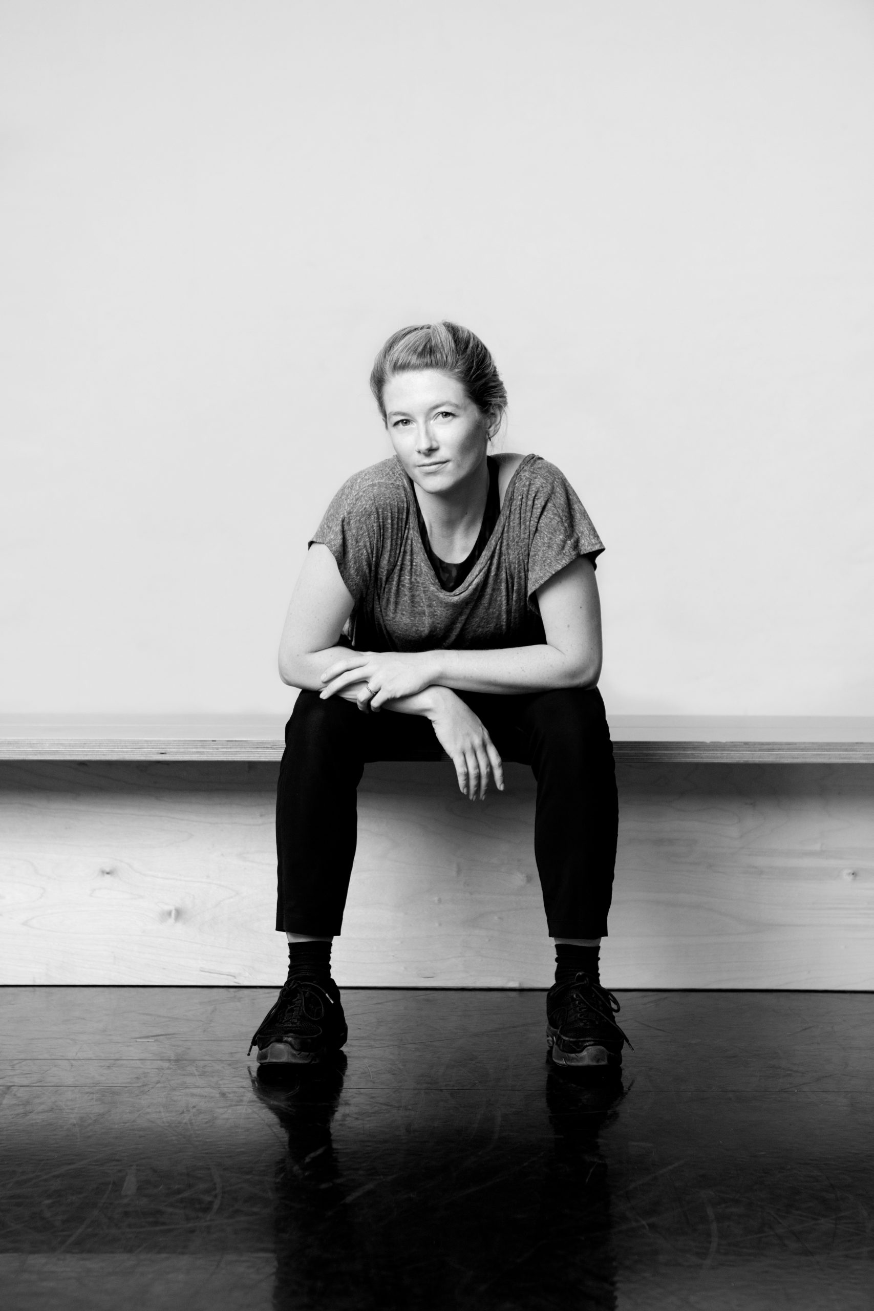 a black and white photo of a woman sitting on the floor.