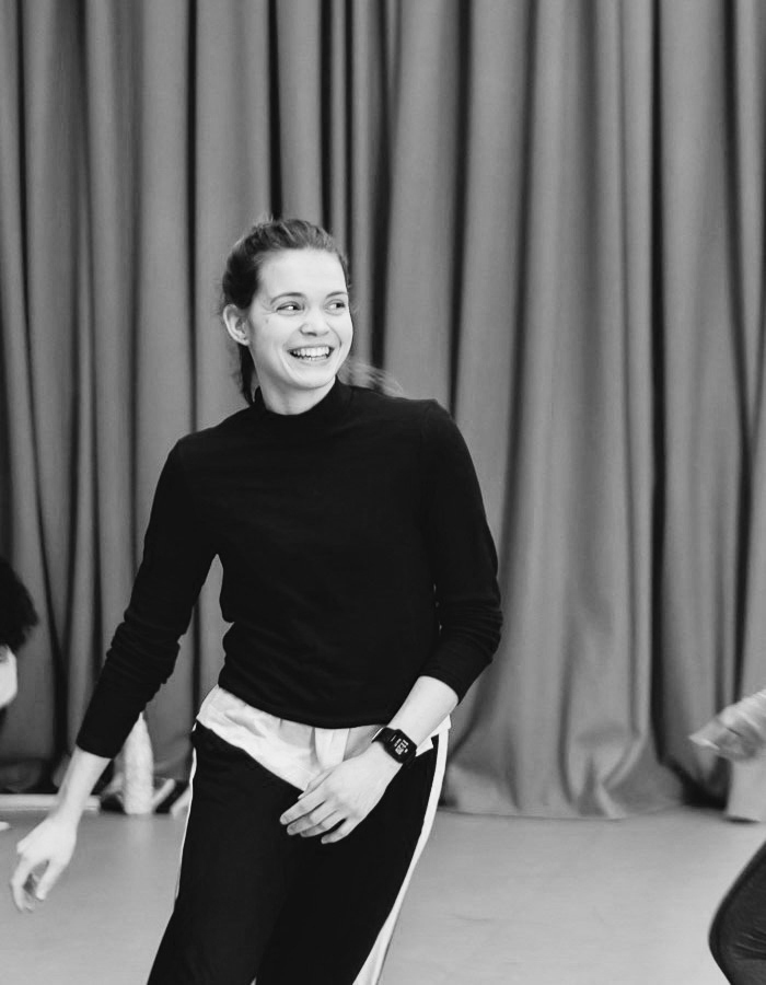 a woman standing in front of a curtain with a smile on her face.