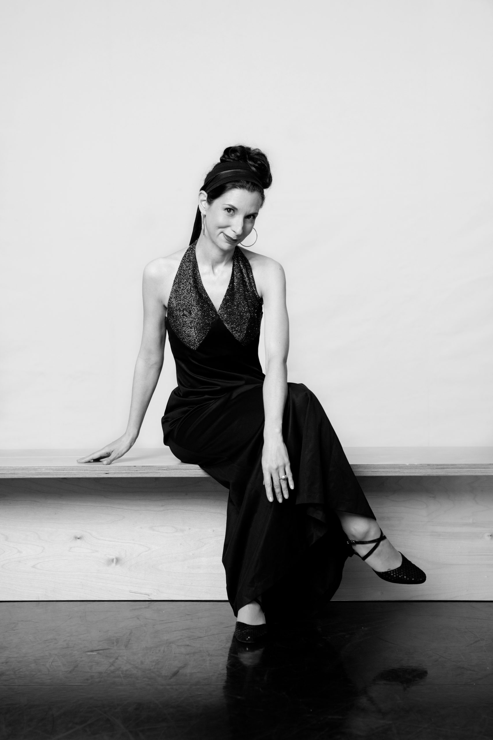 a woman sitting on the floor in a black dress.