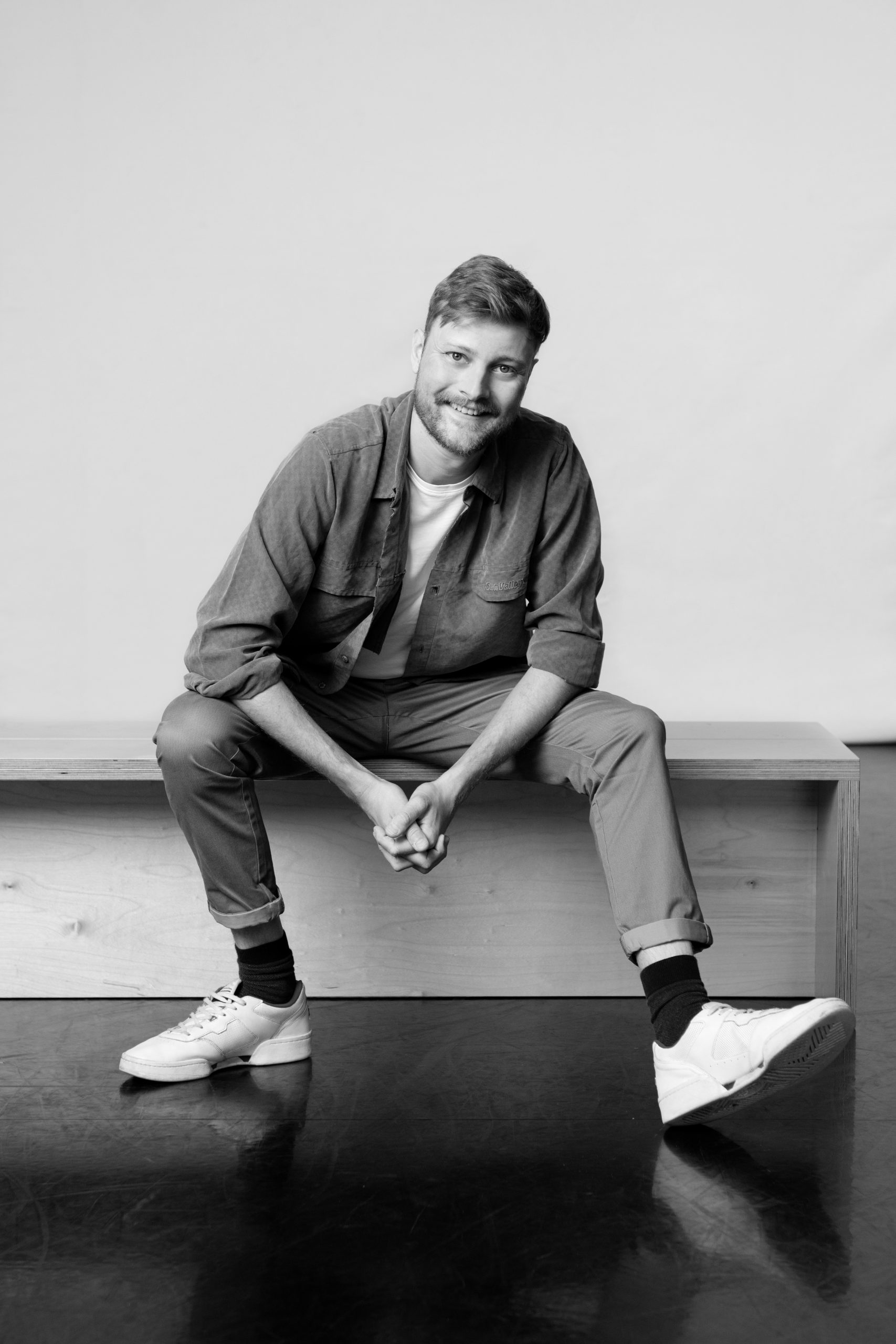 a black and white photo of a man sitting on a bench.