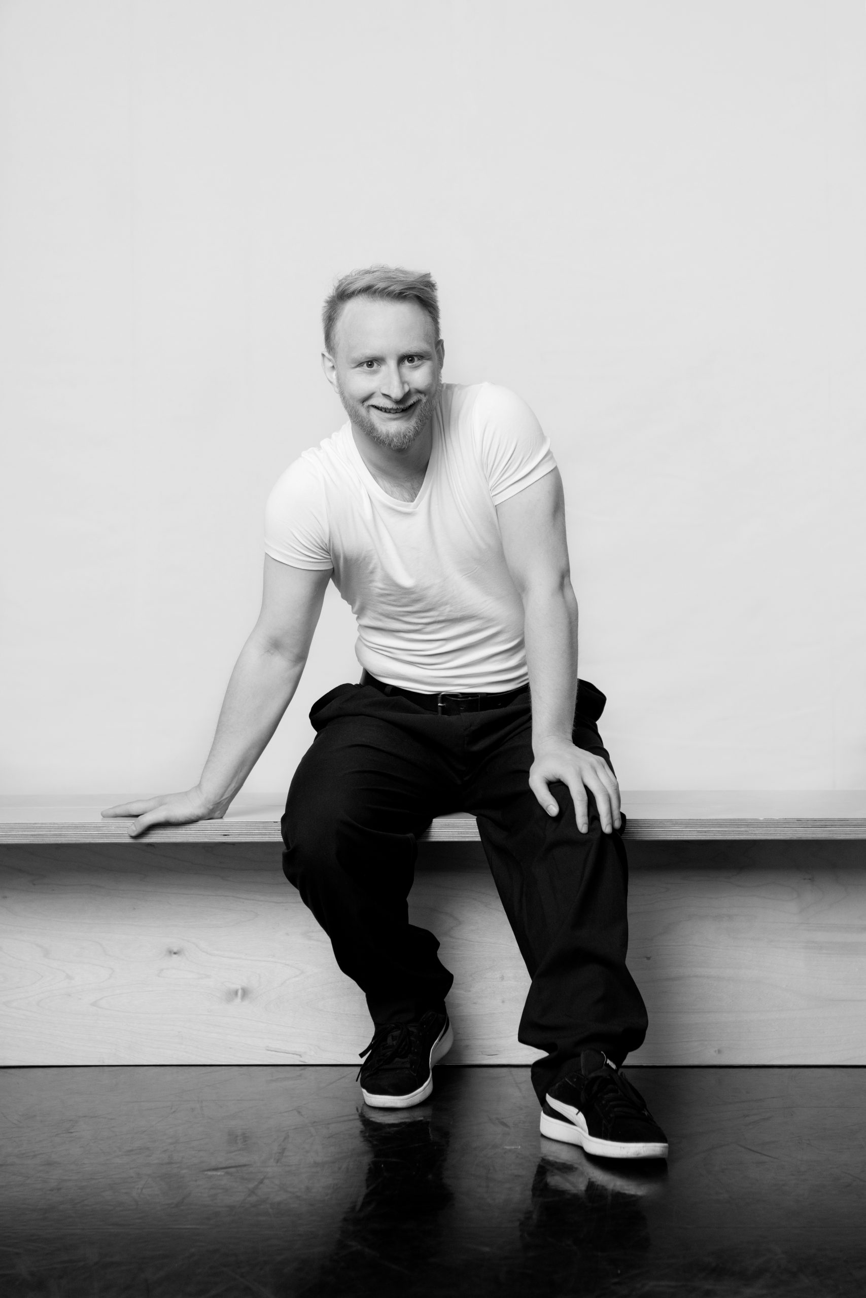 a black and white photo of a man sitting on the floor.