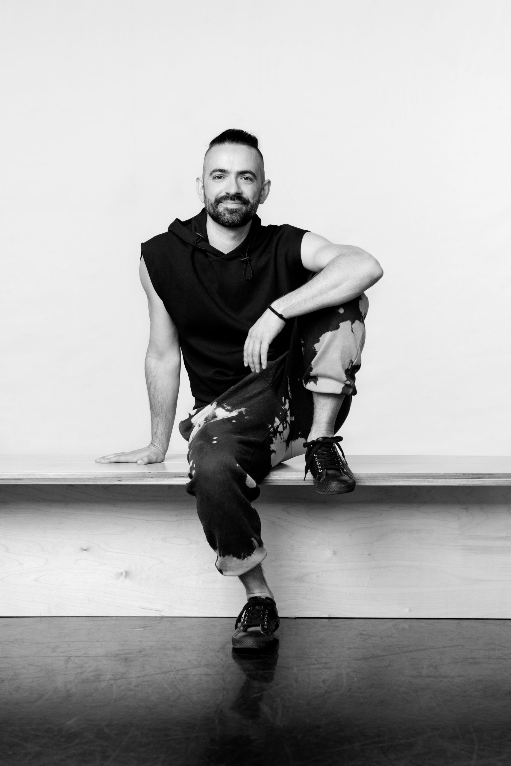 a black and white photo of a man sitting on a ledge.