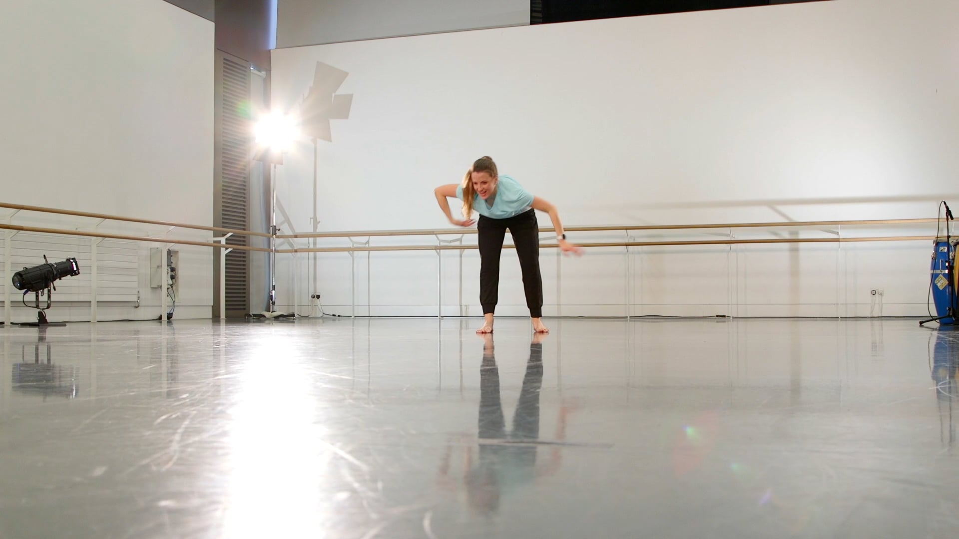 a woman in a blue shirt is doing a ballet move.