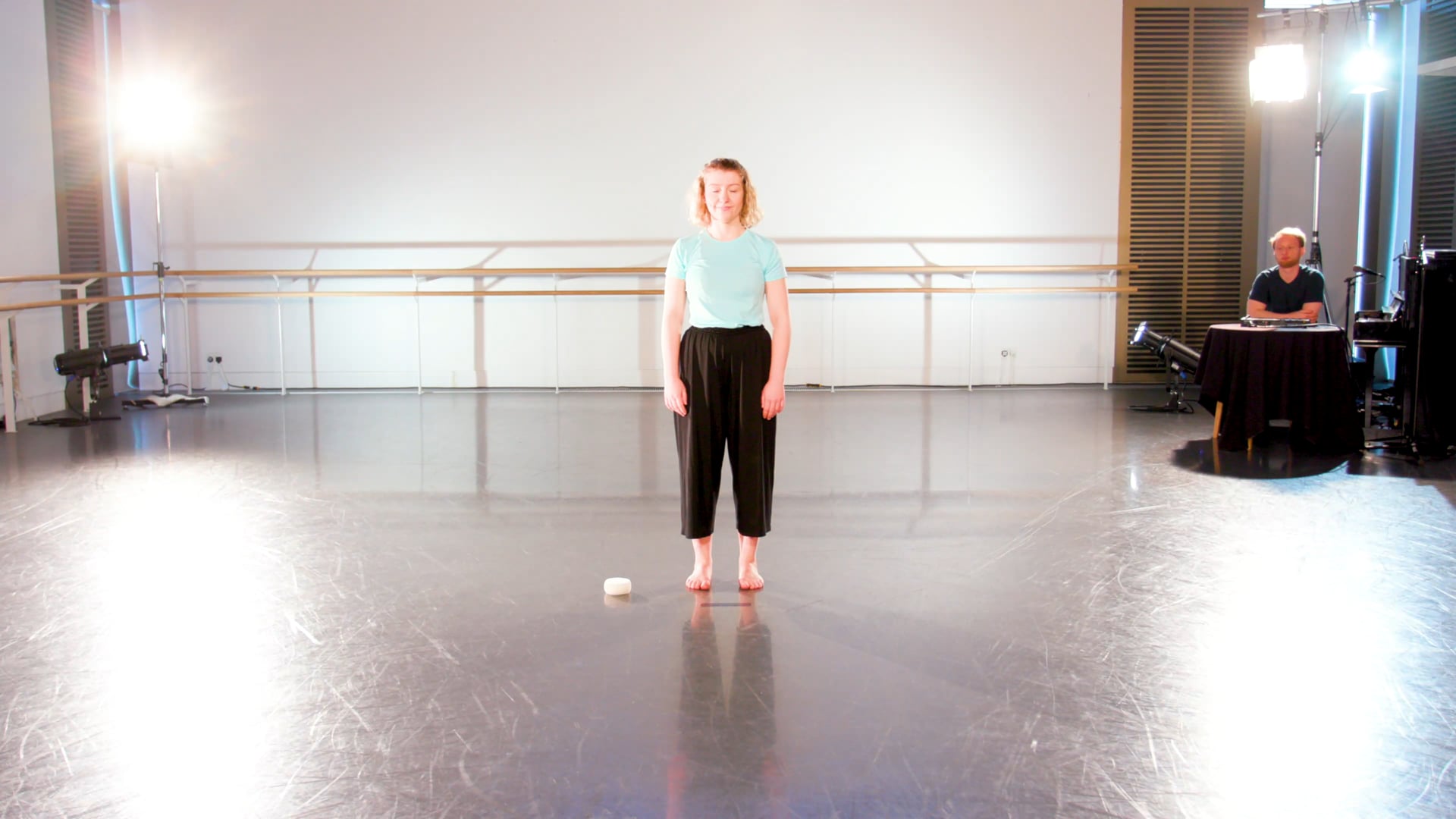a woman standing on a stage in a dance studio.