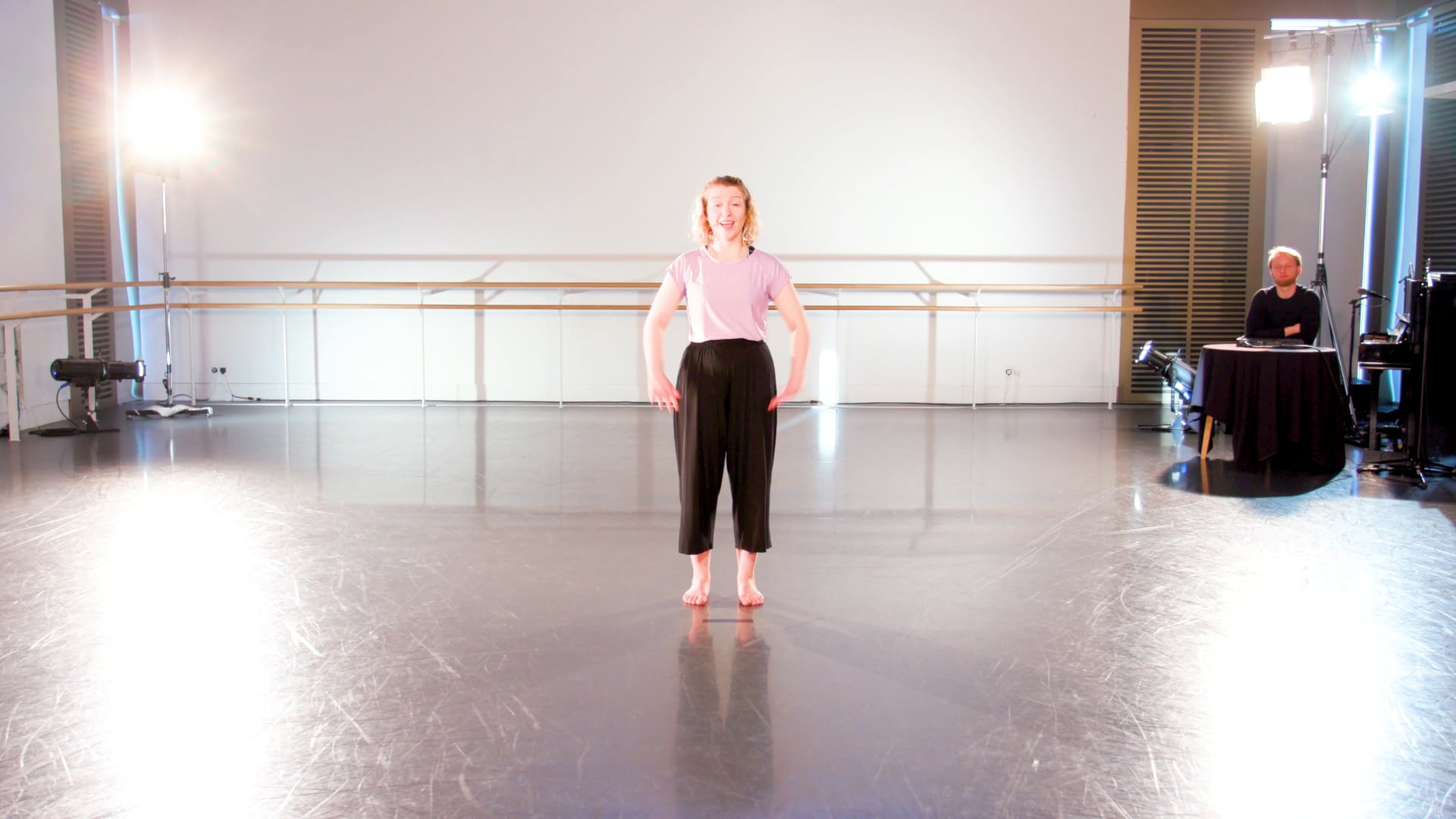 a woman standing on a stage in a dance studio.