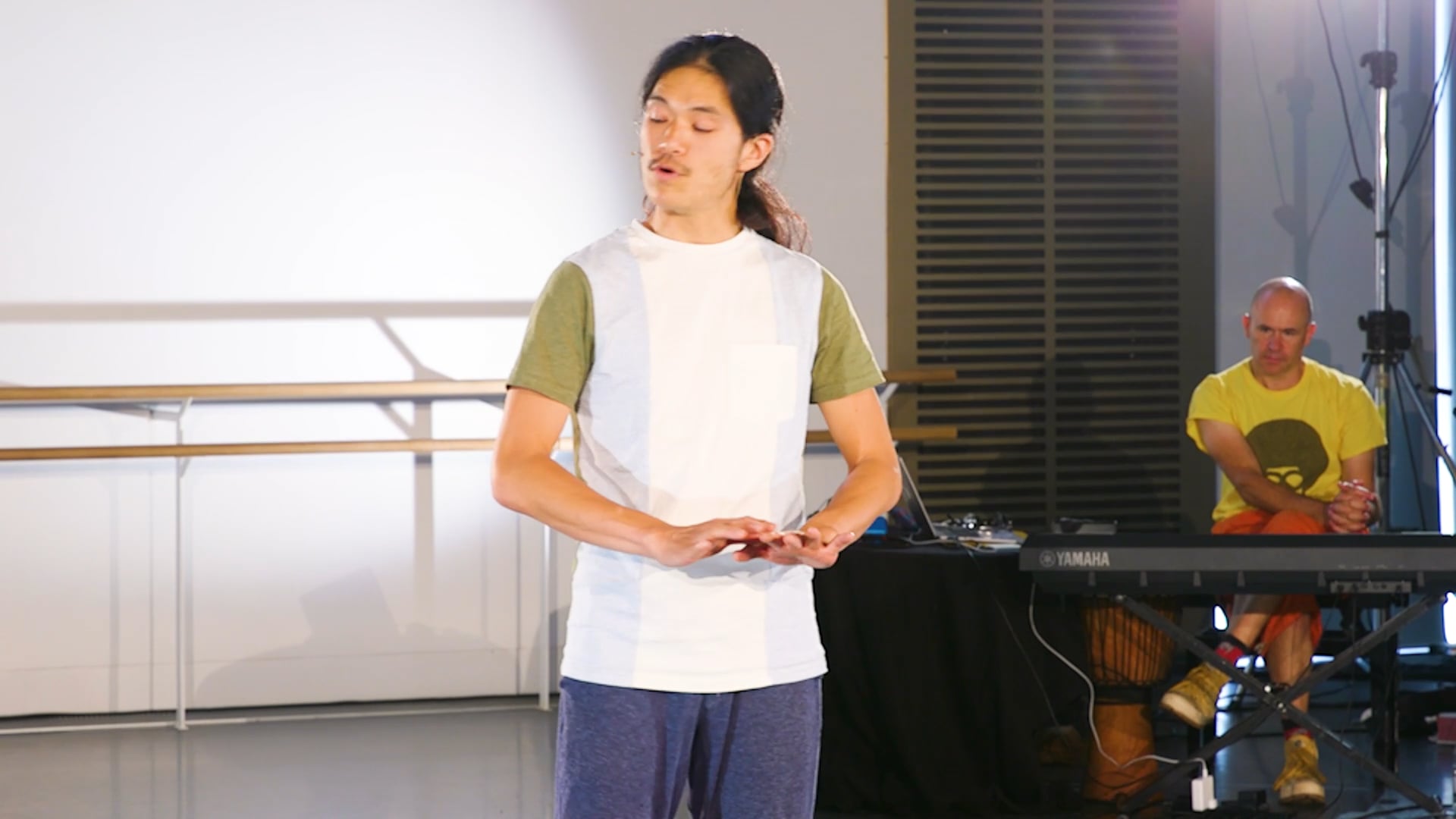 a man standing on a stage with his hands in his pockets.