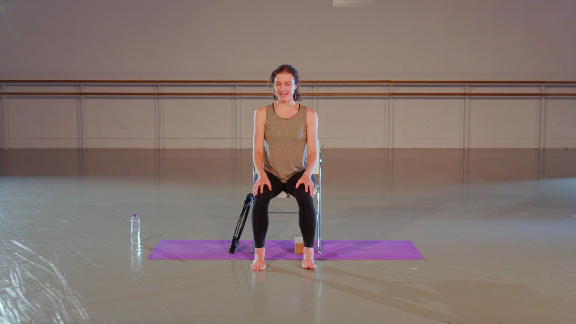 a woman standing on a purple mat with a tennis racket.