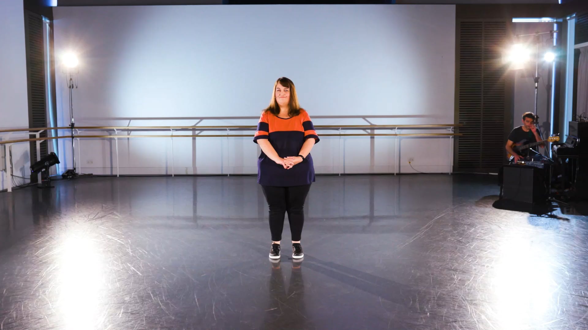 a woman standing on a stage in a dance studio.