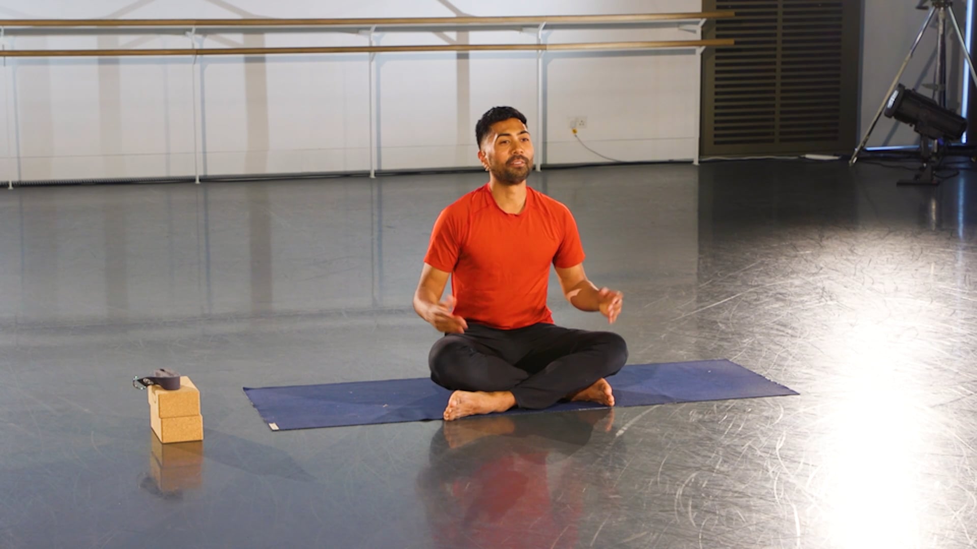 a man sitting on a yoga mat in a room.