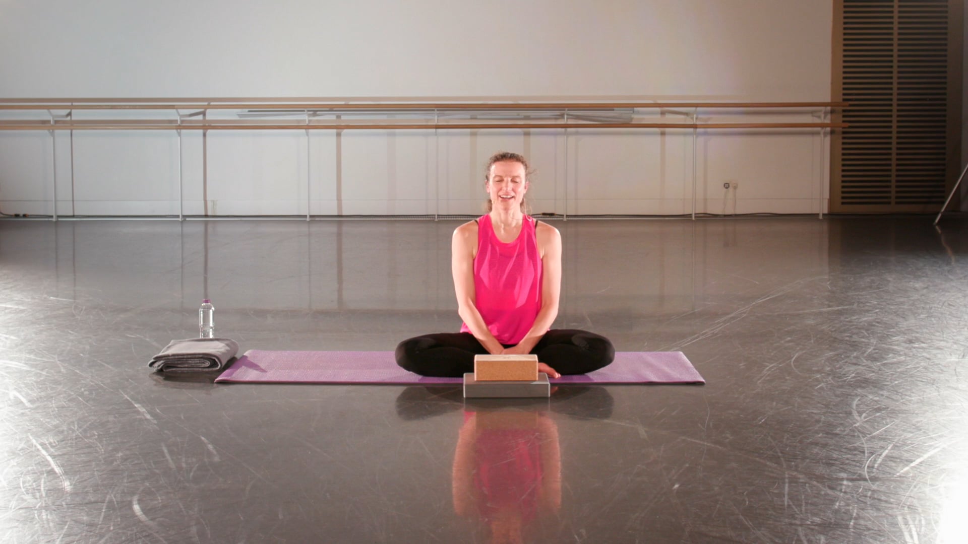 a woman sitting on a yoga mat in a gym.