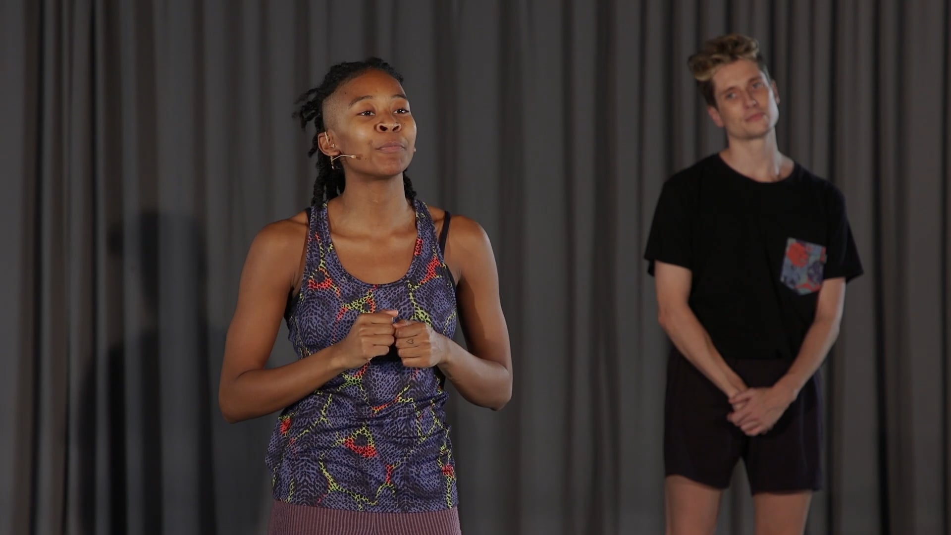 a woman standing next to a man in front of a curtain.