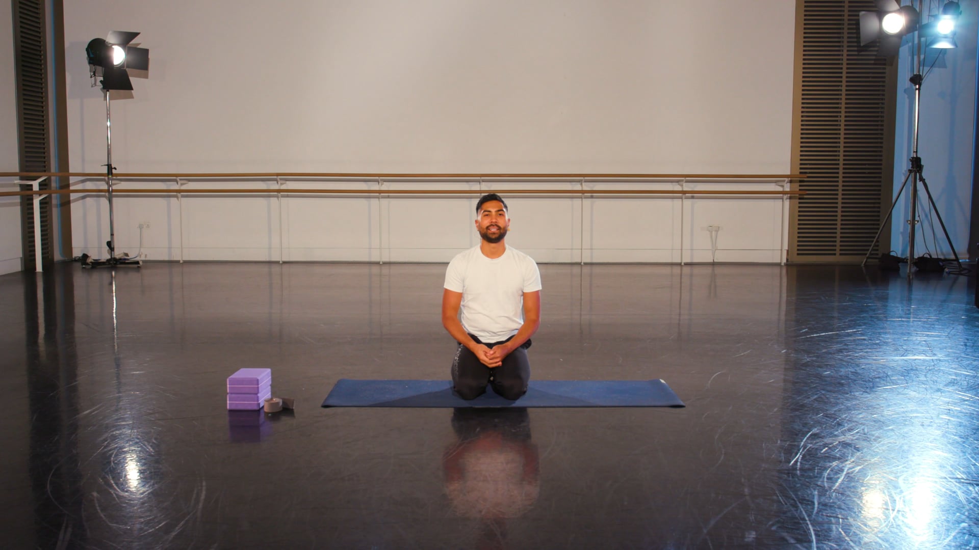 a man sitting on a yoga mat in a room.