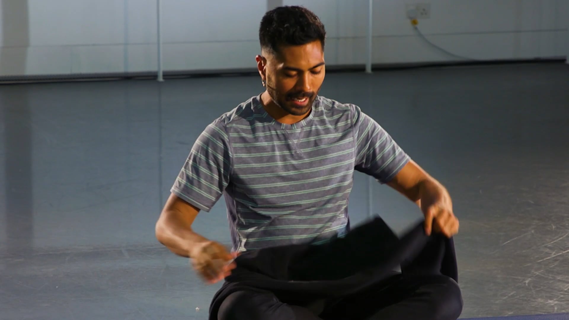 a man sitting on the ground holding a piece of cloth.