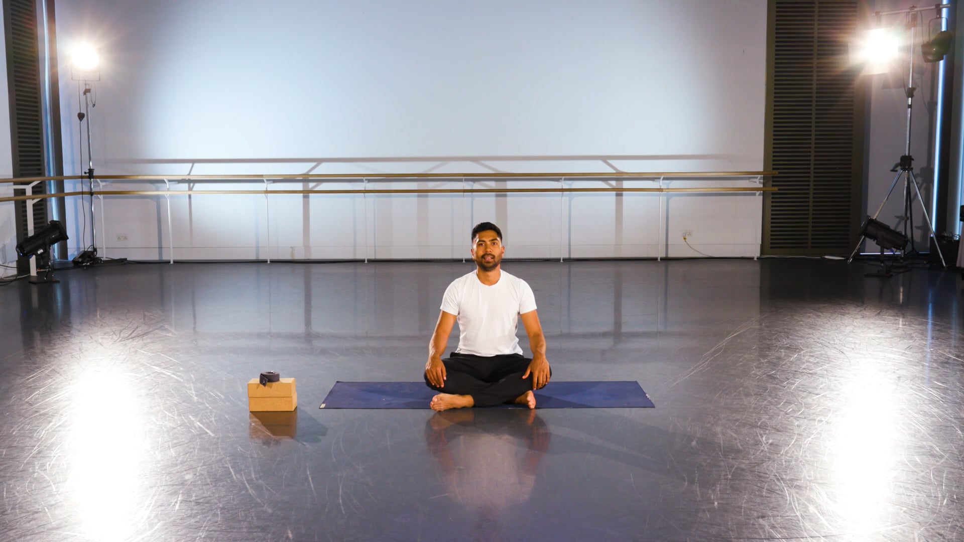 a man sitting on a yoga mat in a room.