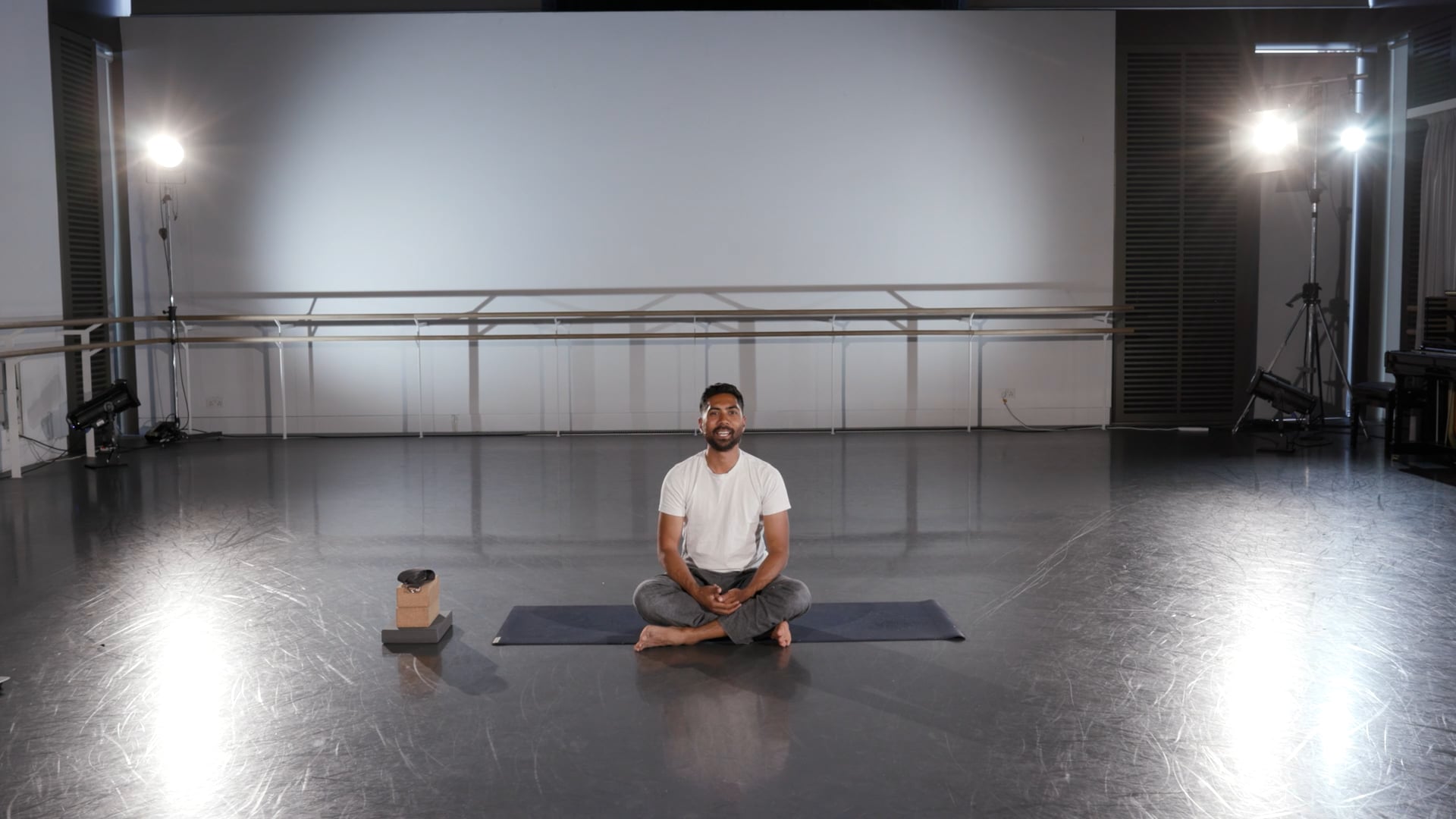 a man sitting on a yoga mat in a room.