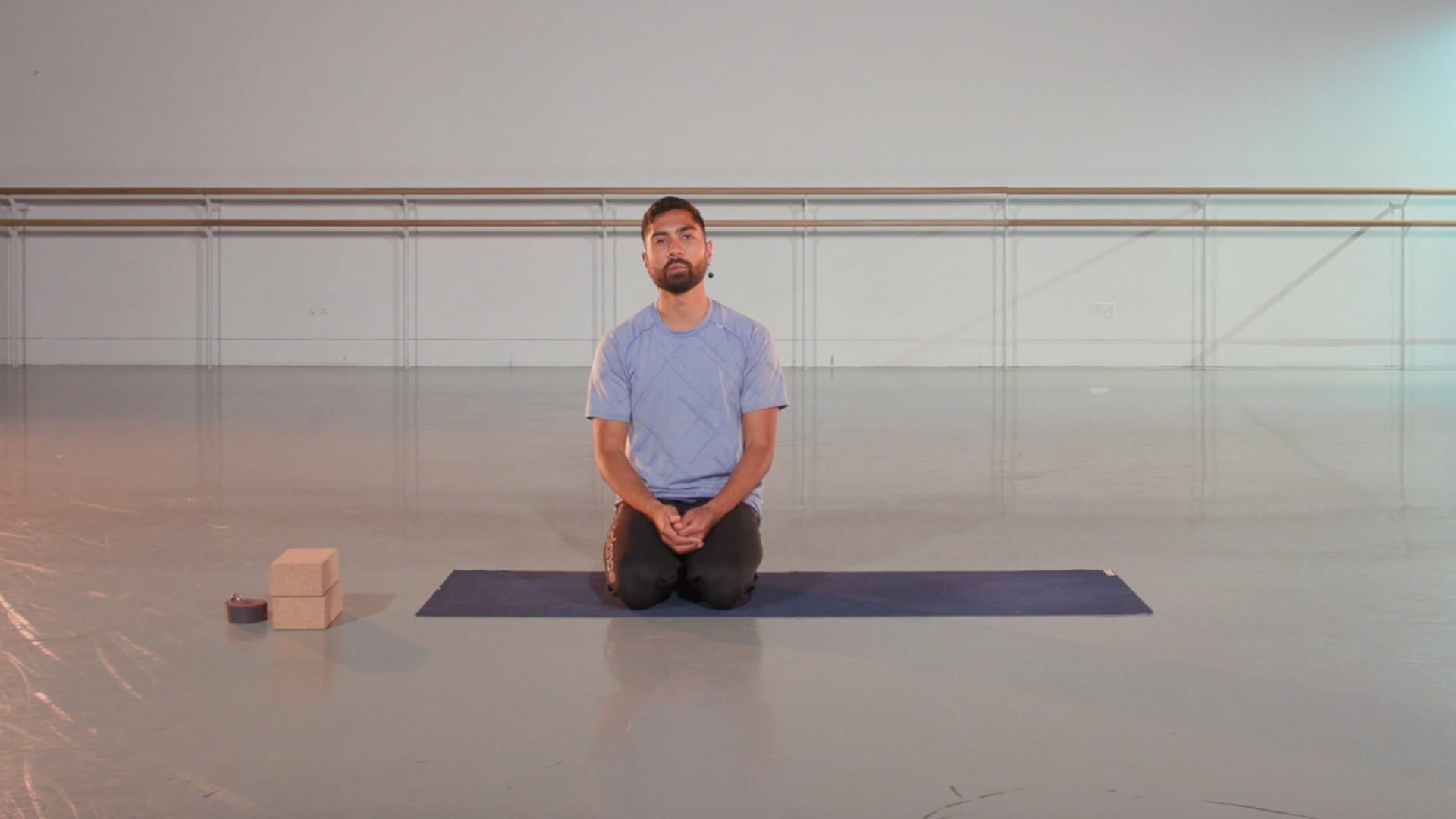 a man sitting on a yoga mat in a large room.