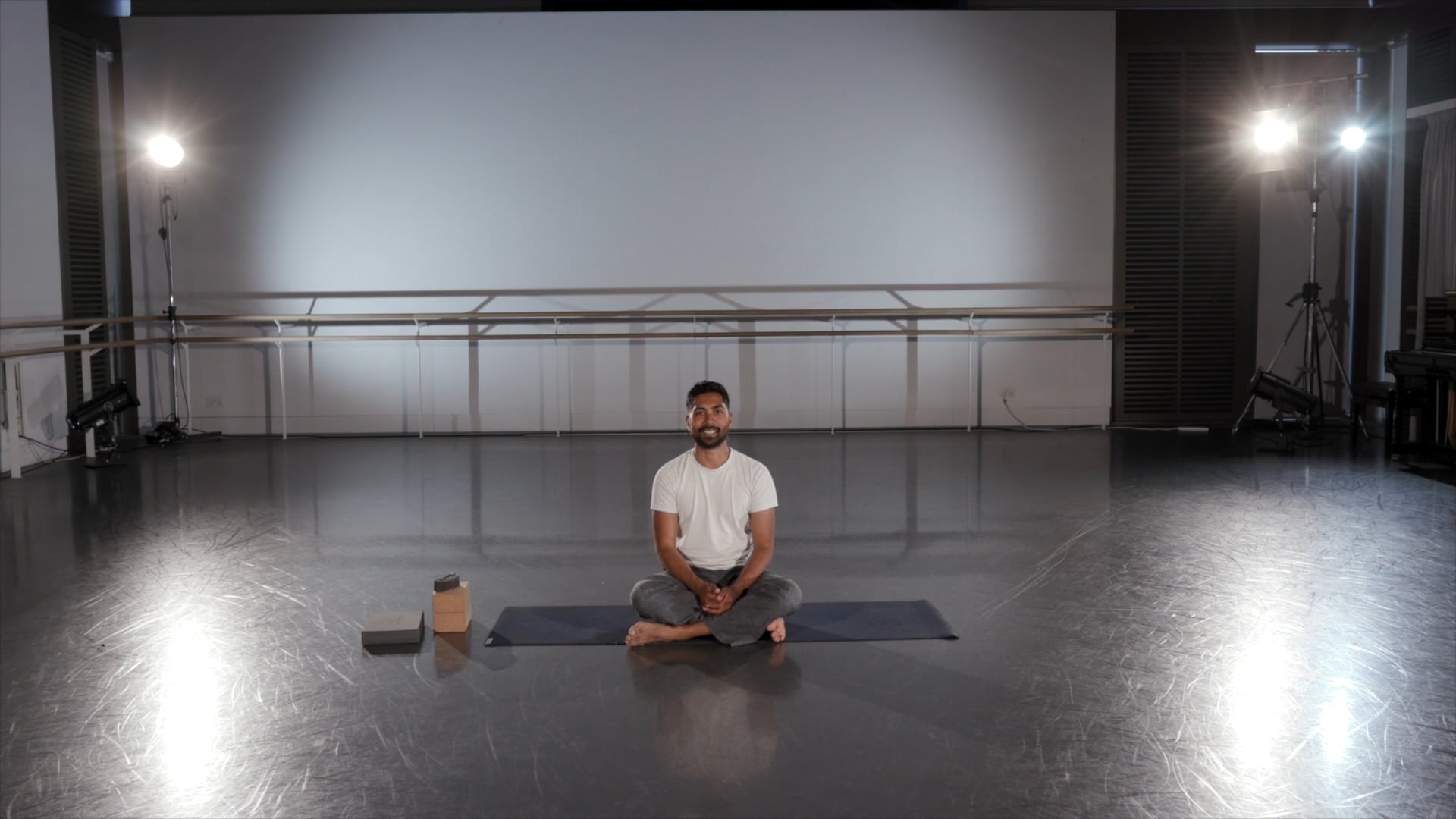 a man sitting on a yoga mat in a room.