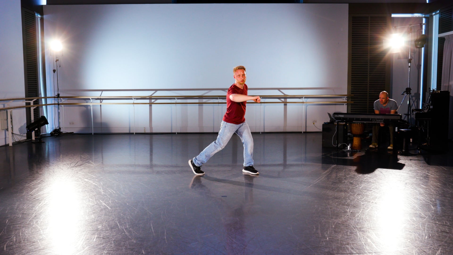 a man in a red shirt is dancing on a stage.