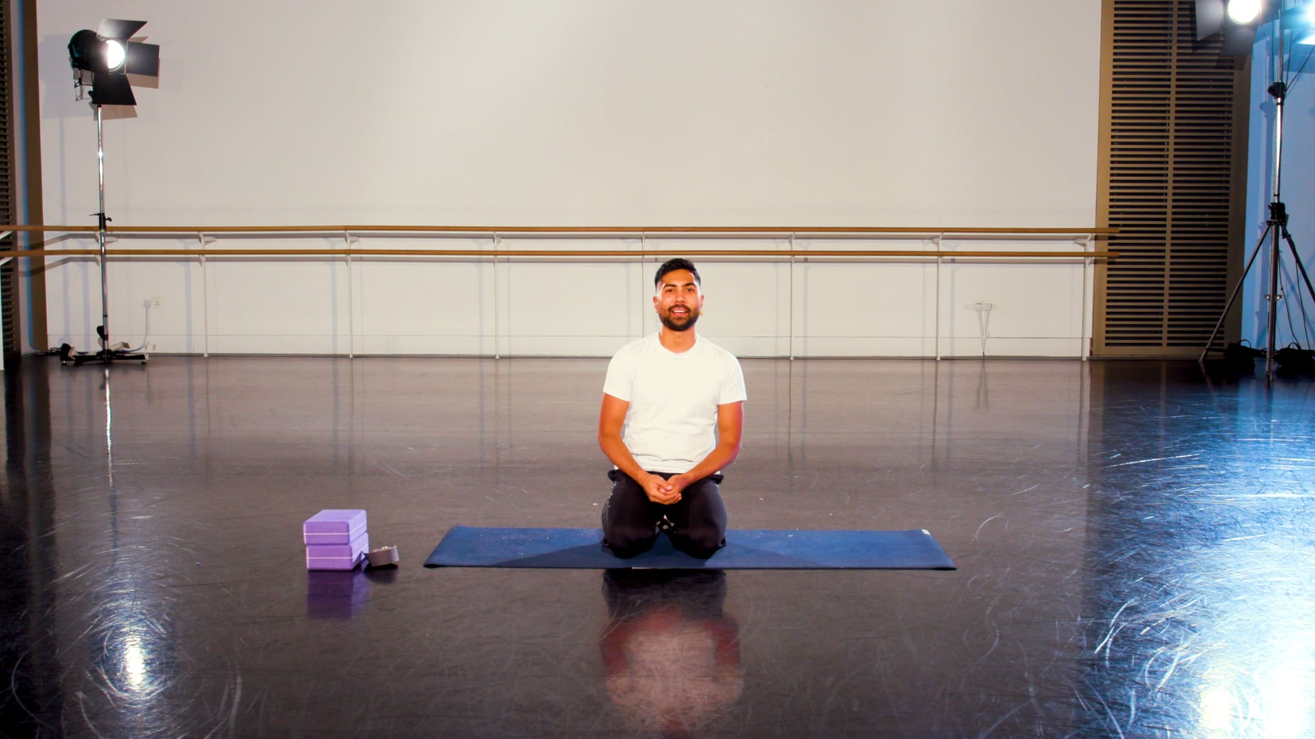 a man sitting on a yoga mat in a room.