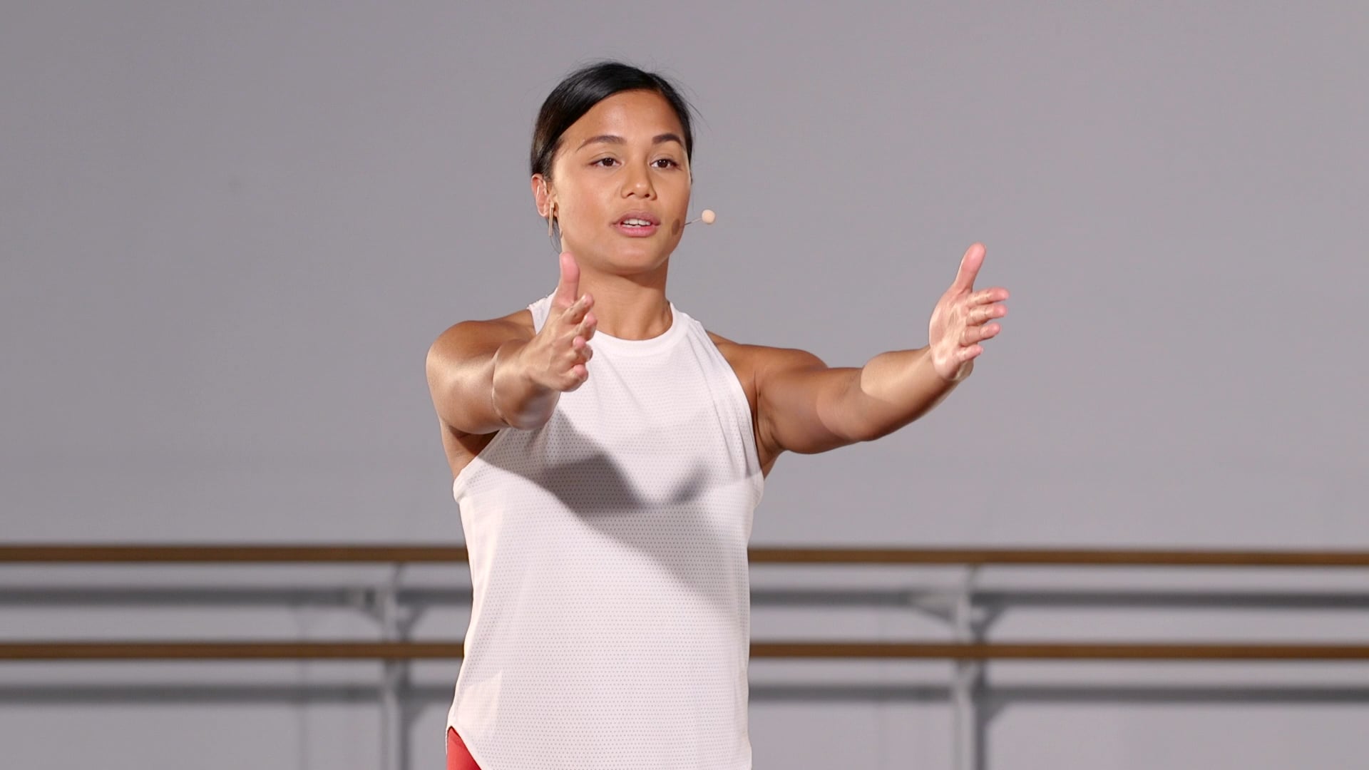 a woman in a white tank top is holding her hands out.