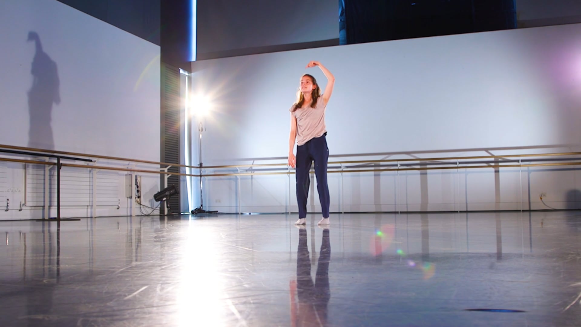 a woman standing on a dance floor with her arms in the air.
