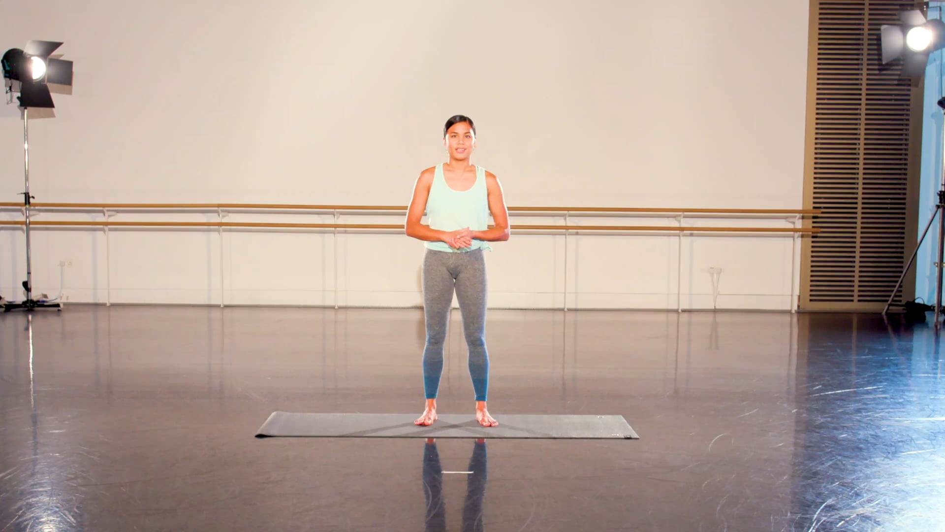 a woman standing on a mat in a dance studio.