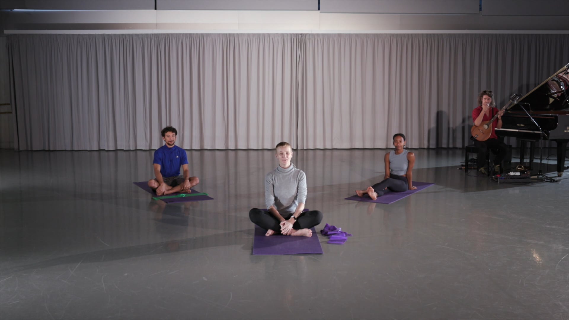 a group of people sitting on yoga mats in front of a piano.