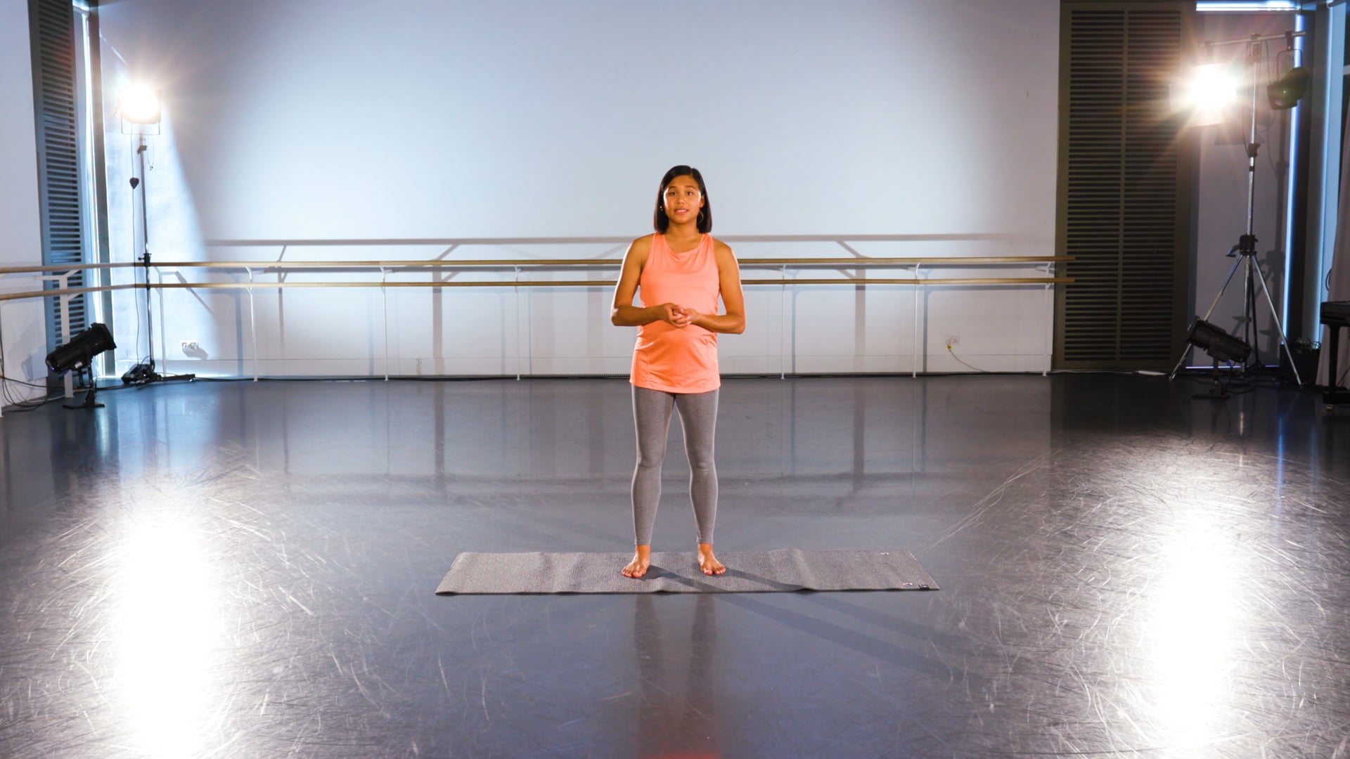 a woman standing on a mat in a dance studio.