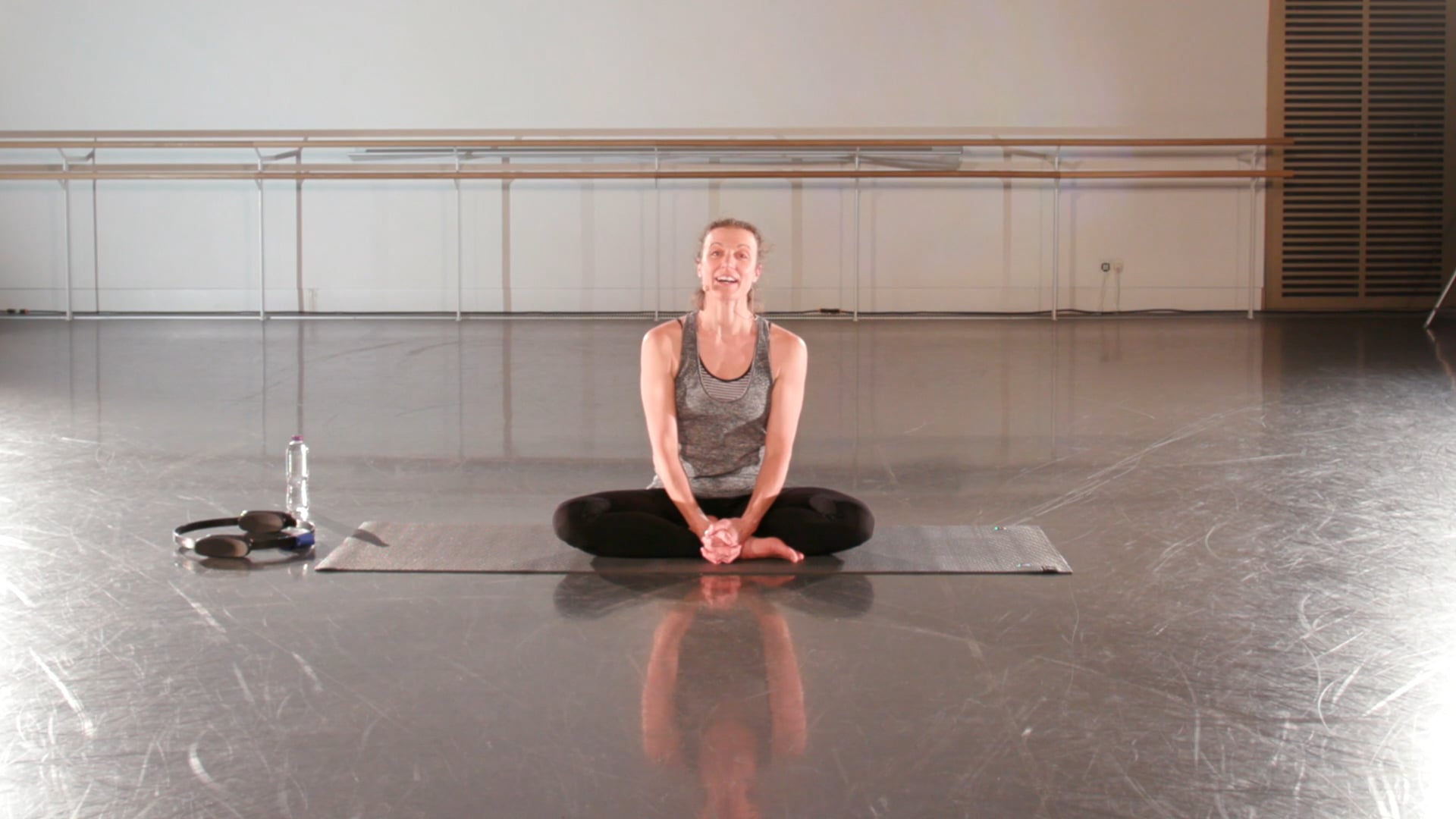 a woman sitting on a yoga mat in a gym.