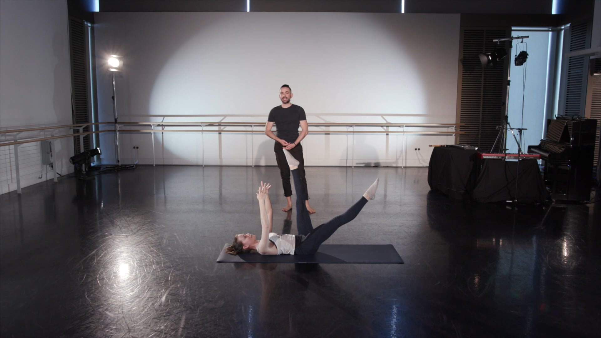 a man standing on top of a yoga mat next to a woman laying on the.