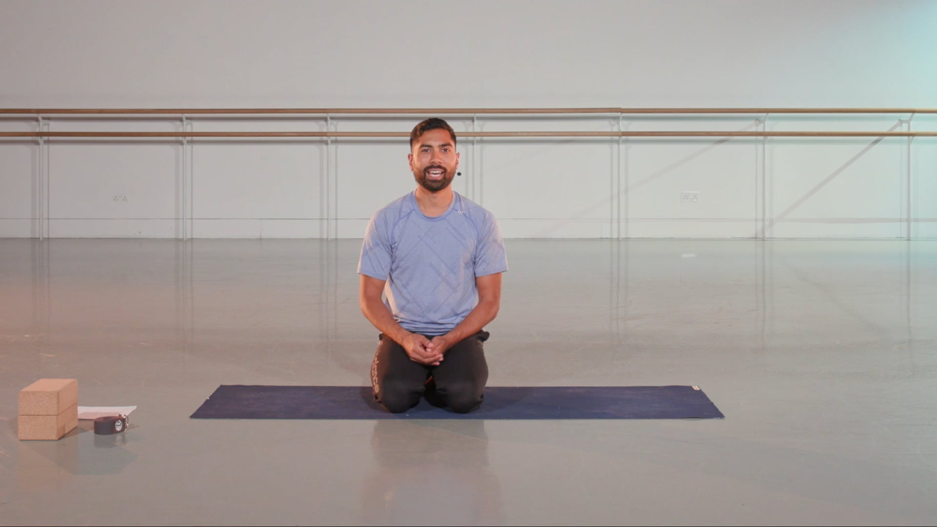 a man sitting on a yoga mat in a room.