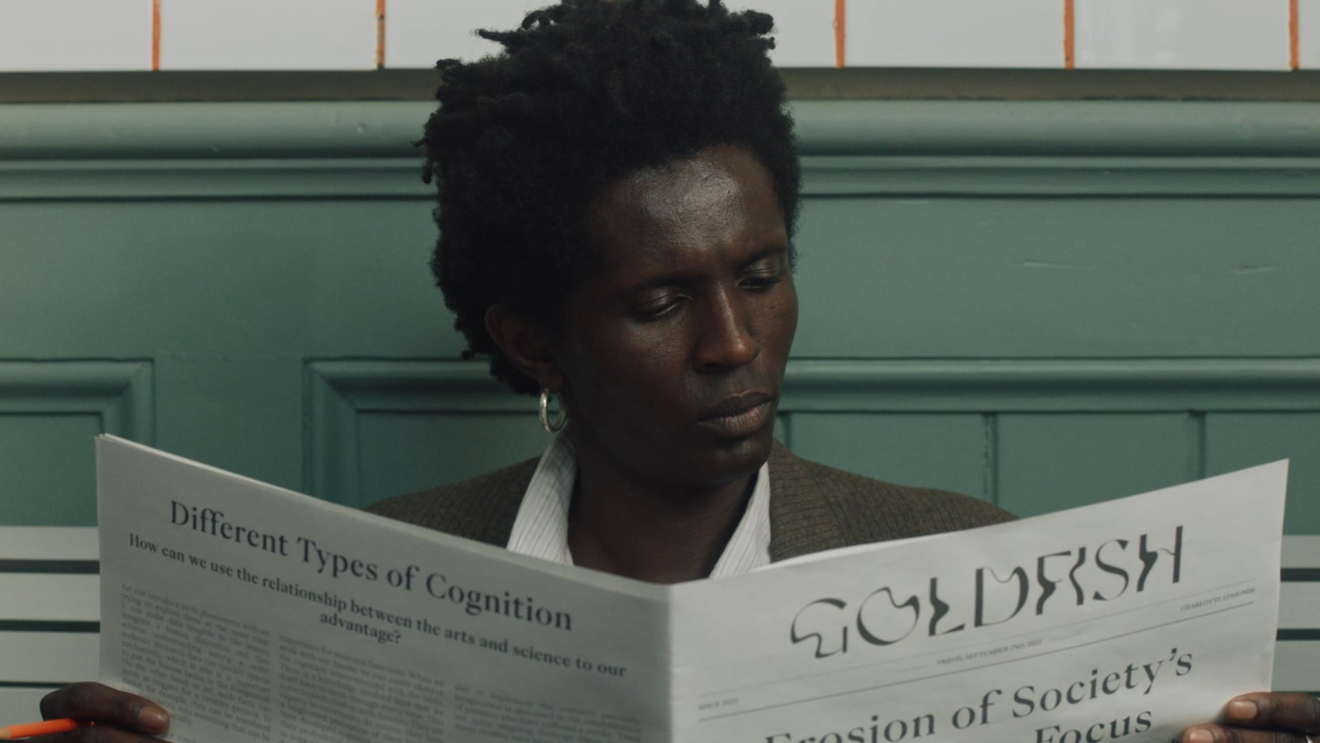 a woman reading a newspaper while sitting on a bench.