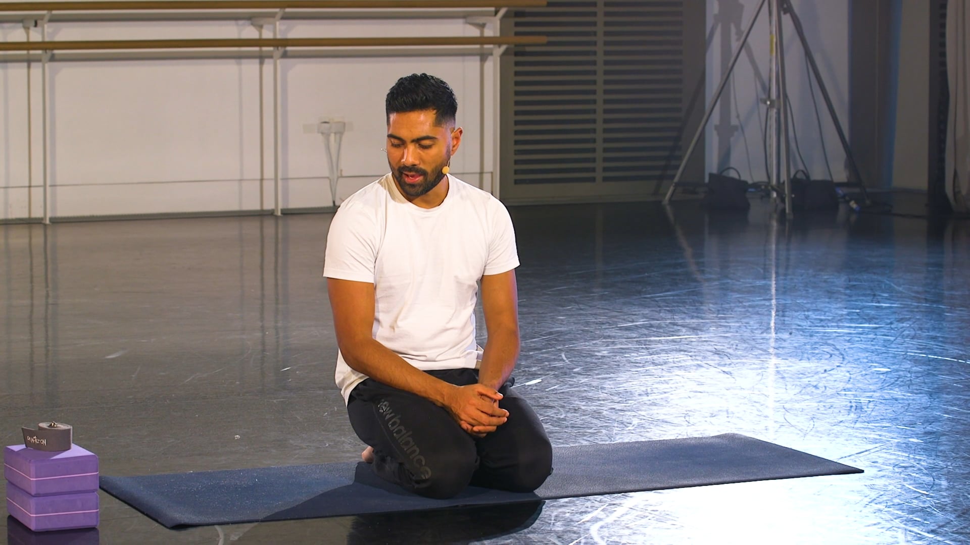 a man sitting on a yoga mat in a room.